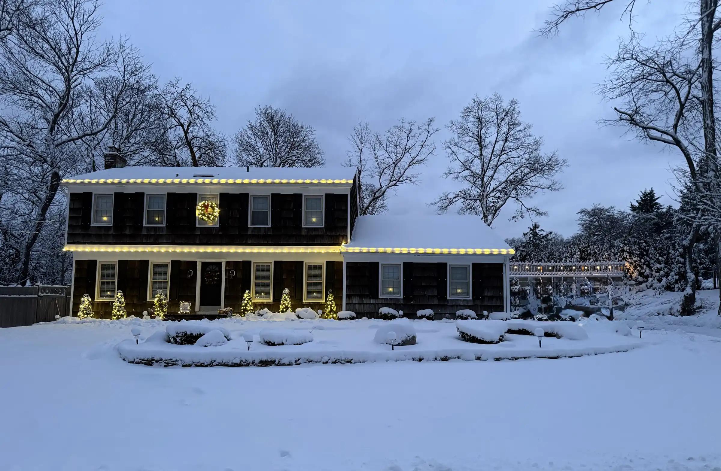 Finished Christmas light installation glowing on a snowy home