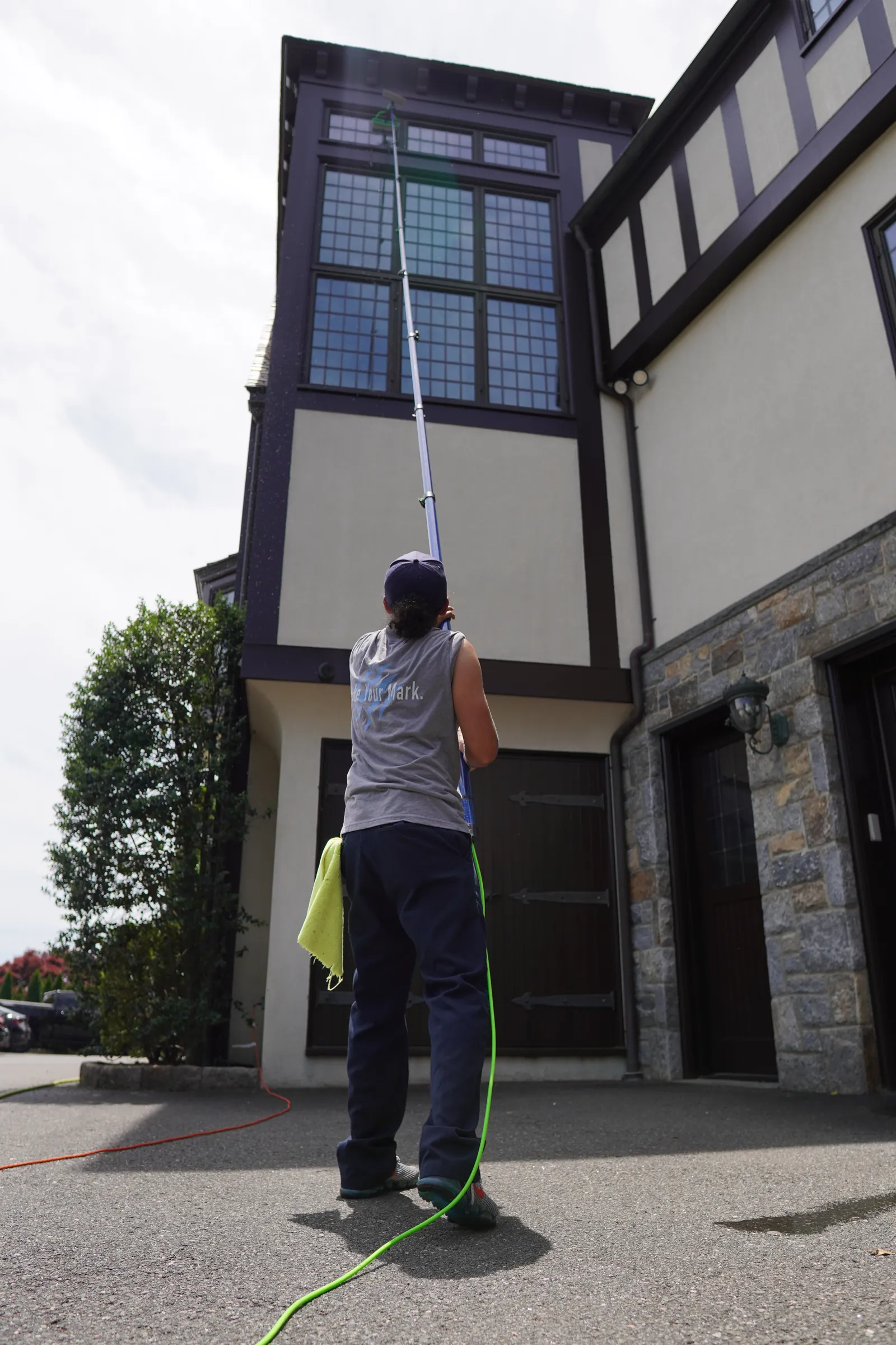 Water-fed pole cleaning upper exterior glass on a Tudor home